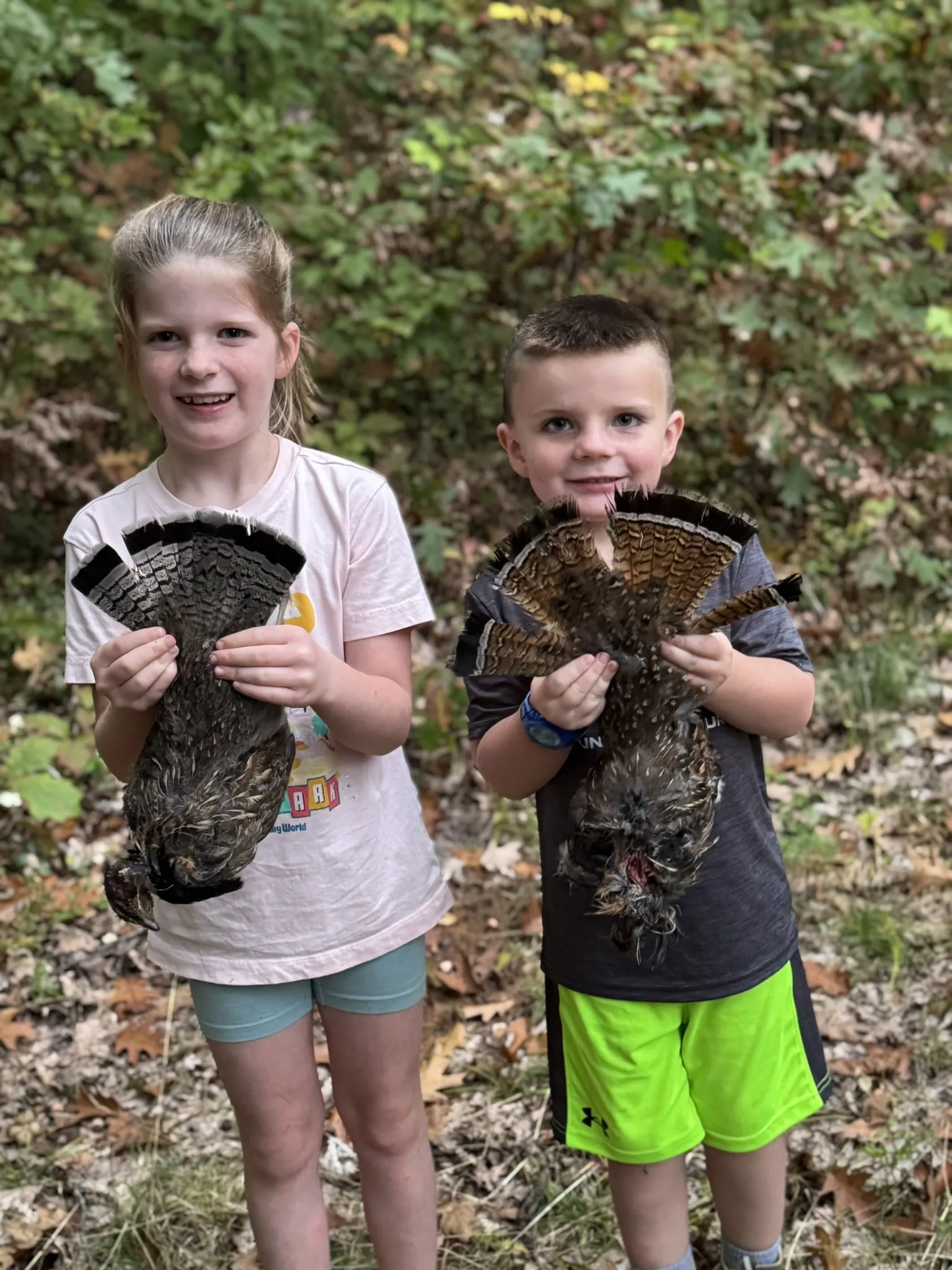 Briella and Inman holding a pair of grouse fans