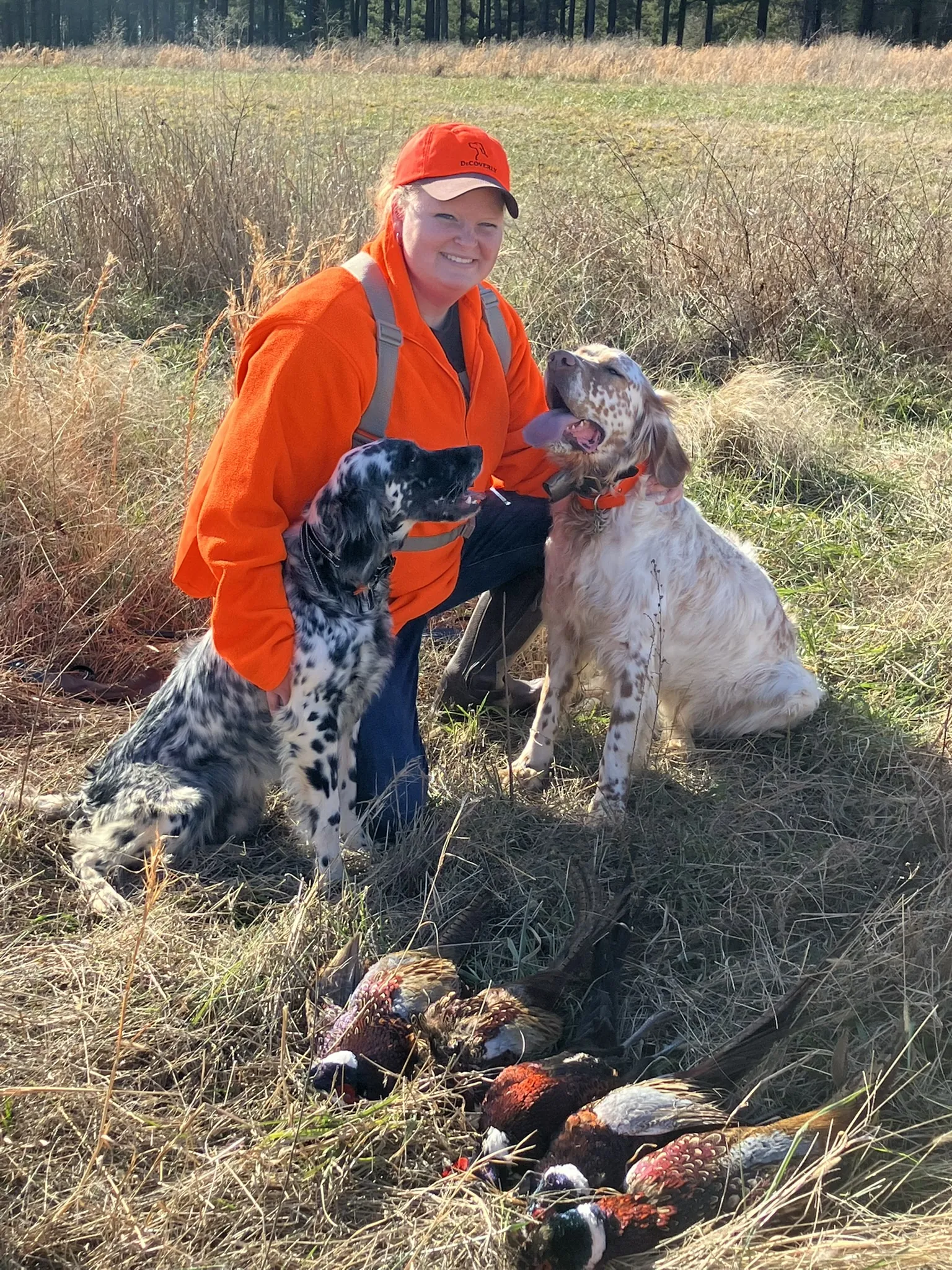 Courtney kneeling with two setters after a preserve hunt